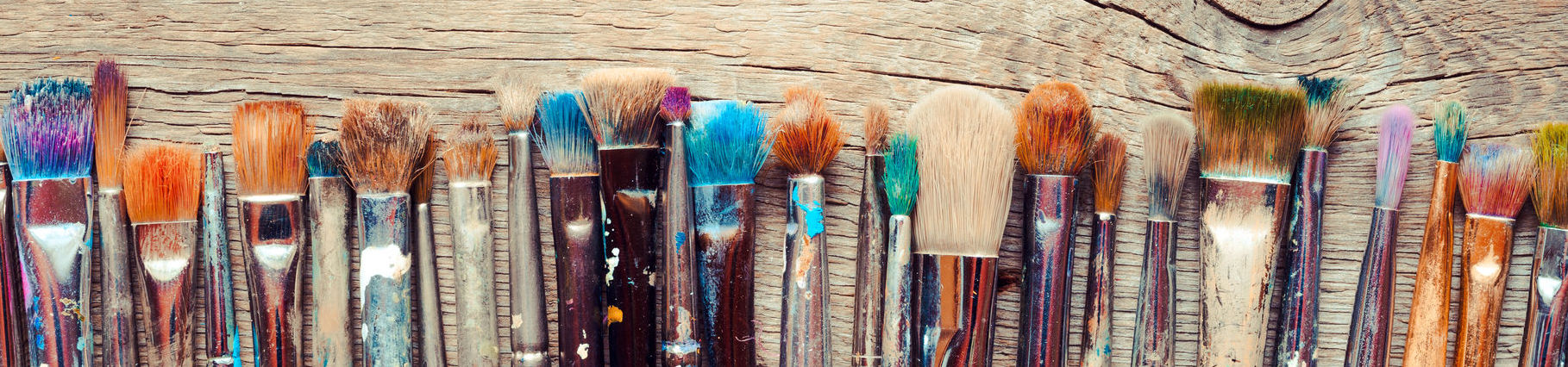 35515339 - row of artist paintbrushes closeup on old wooden rustic background